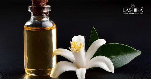 Close-up of orange blossoms and a neroli oil bottle, highlighting the significance of neroli for its refreshing and skin-nourishing properties.