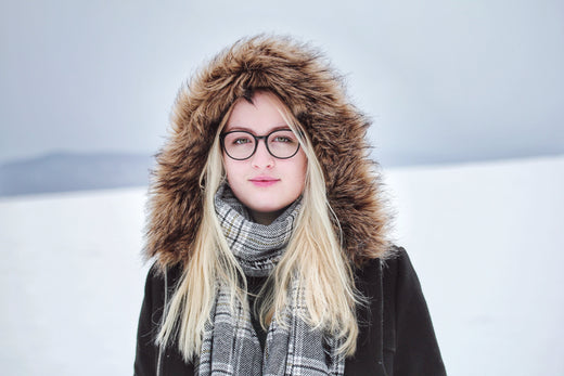 A woman in a fur coat and glasses, showcasing winter skincare while exuding elegance and warmth.